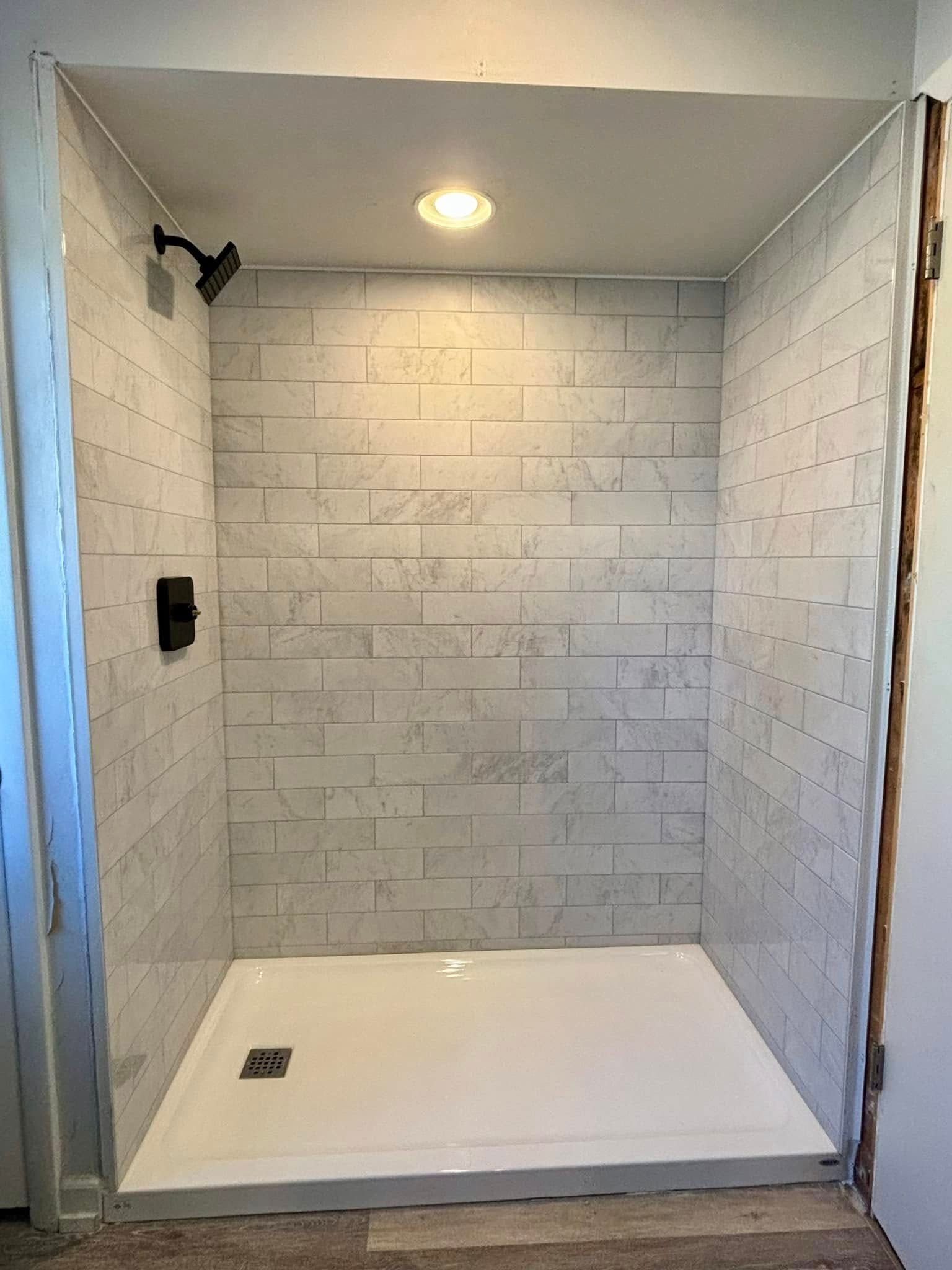 A bathroom with a walk in shower and a brick wall.