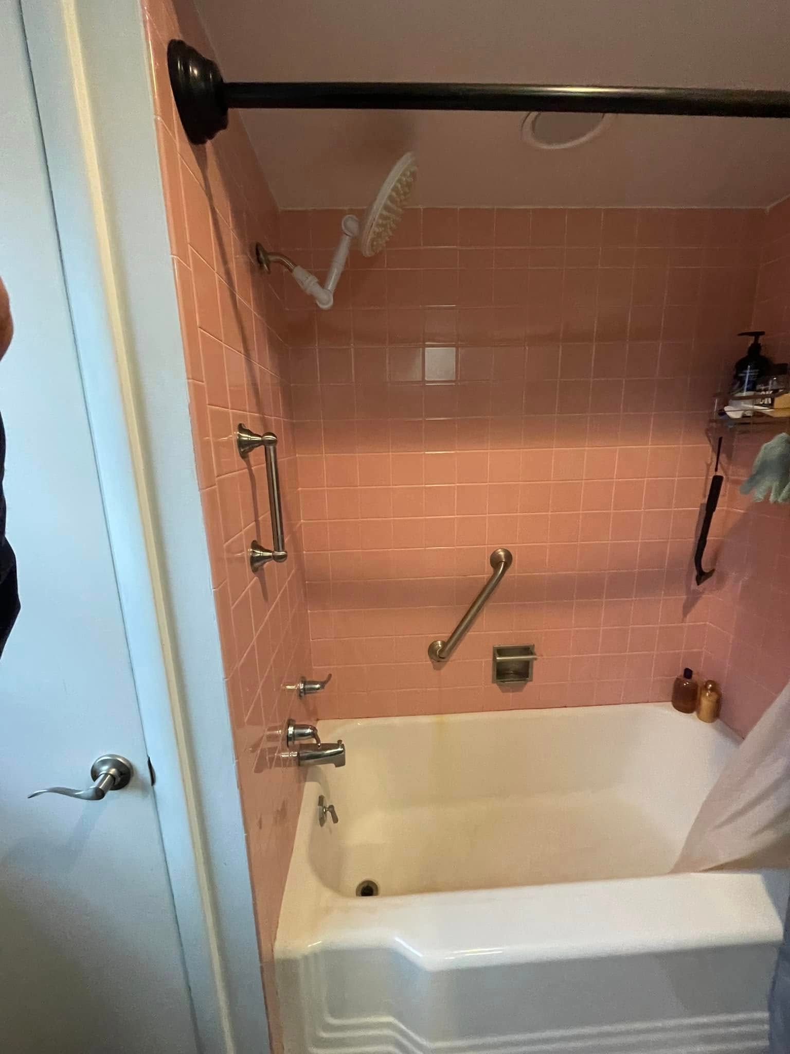 A bathroom with pink tiles and a bathtub and shower.