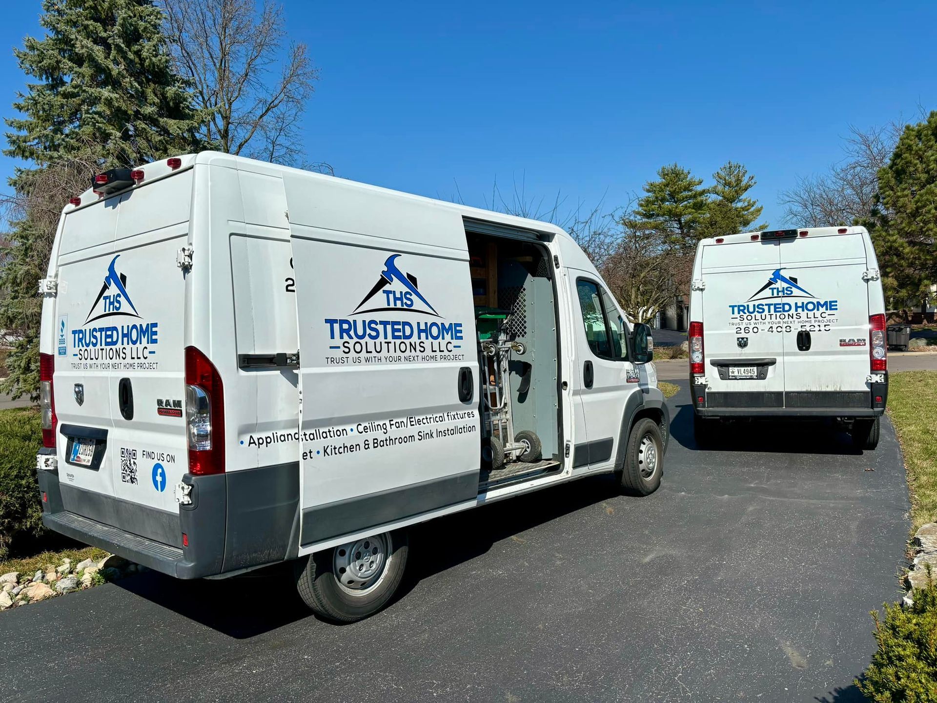 Two white vans are parked next to each other on the side of the road.