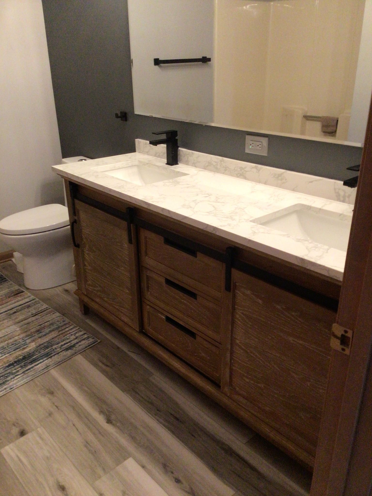 A bathroom with two sinks , a toilet and a mirror.