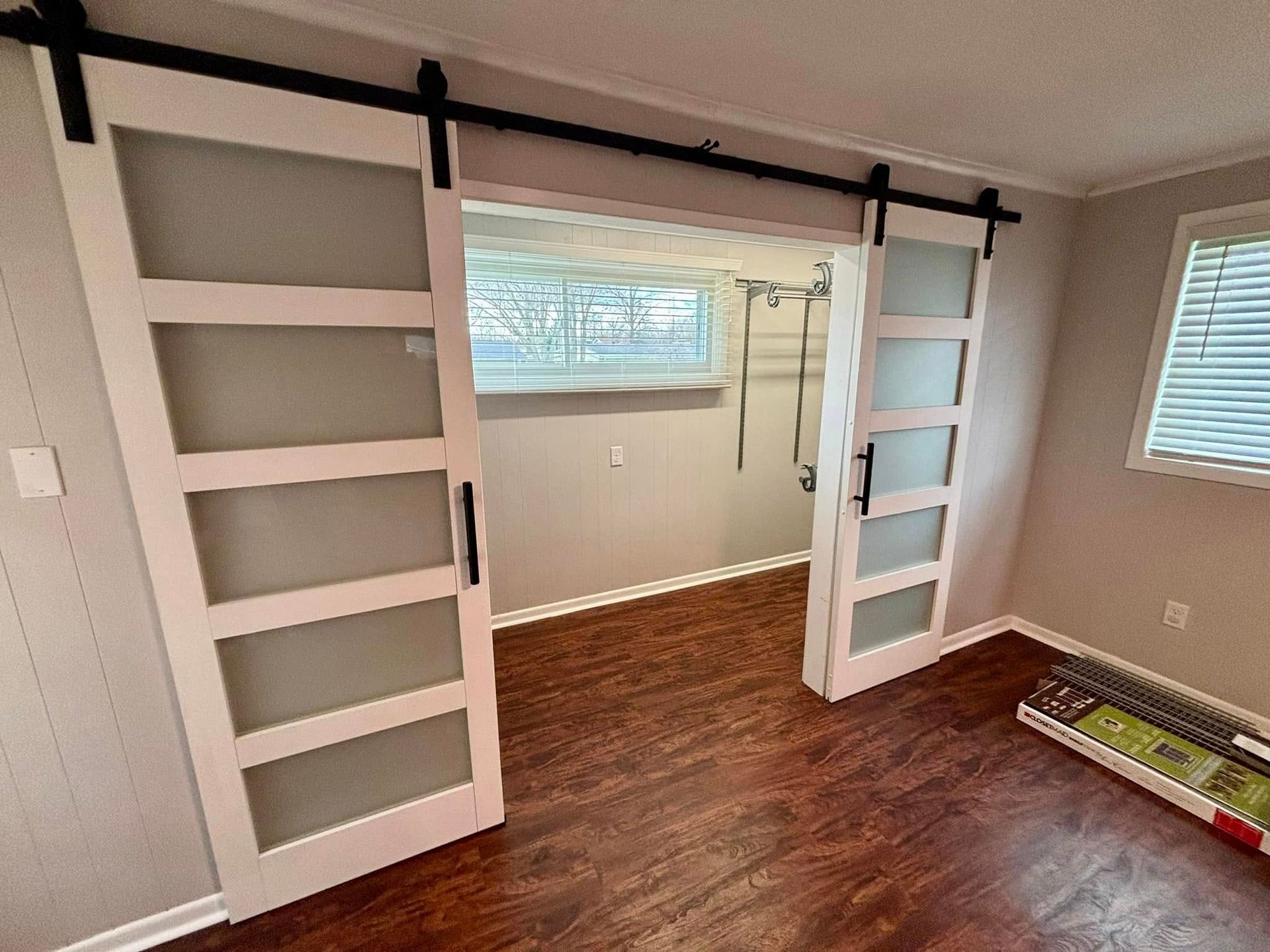 A bedroom with sliding barn doors leading to a basement.