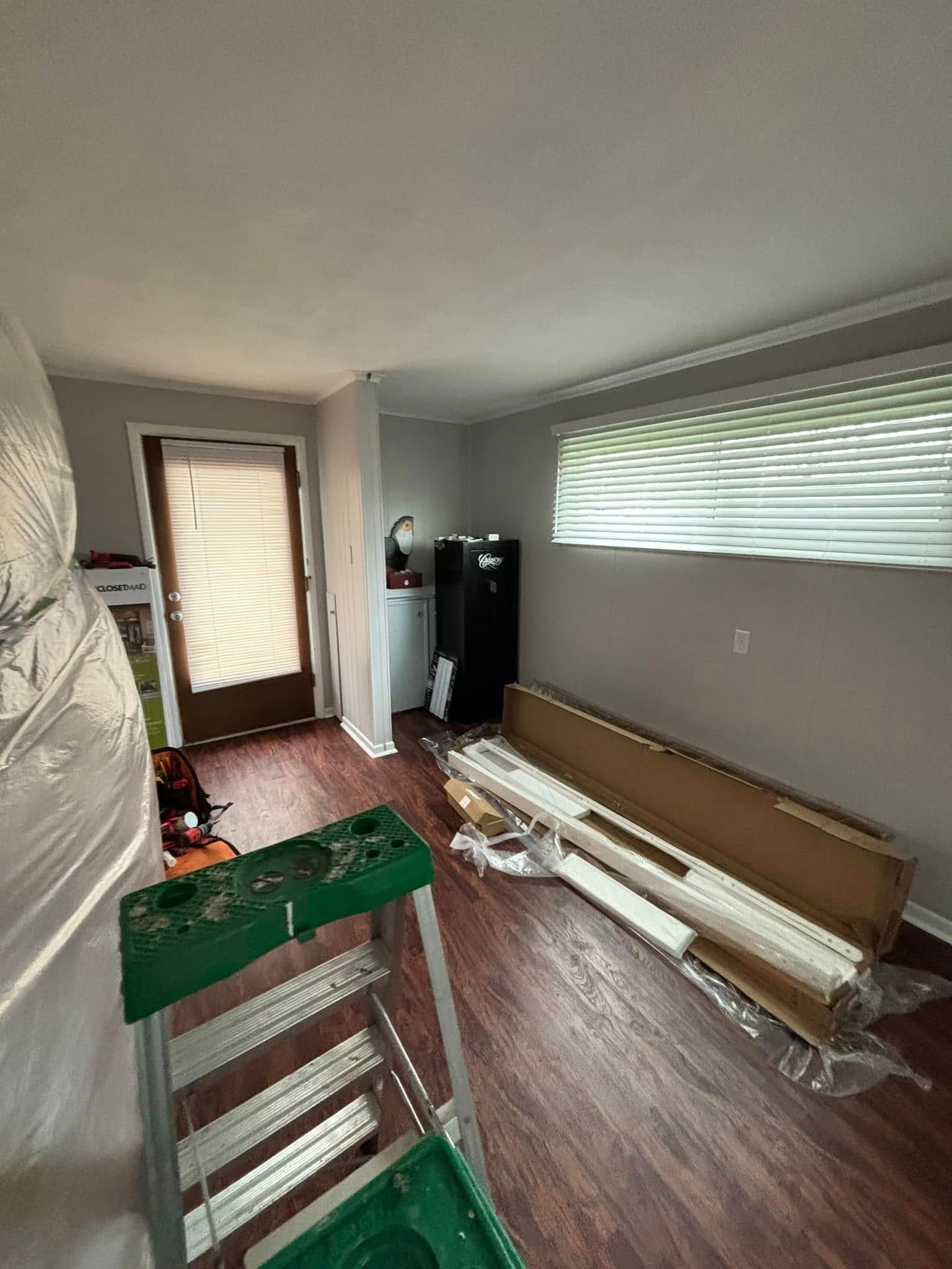 A living room with wooden floors and a green ladder.