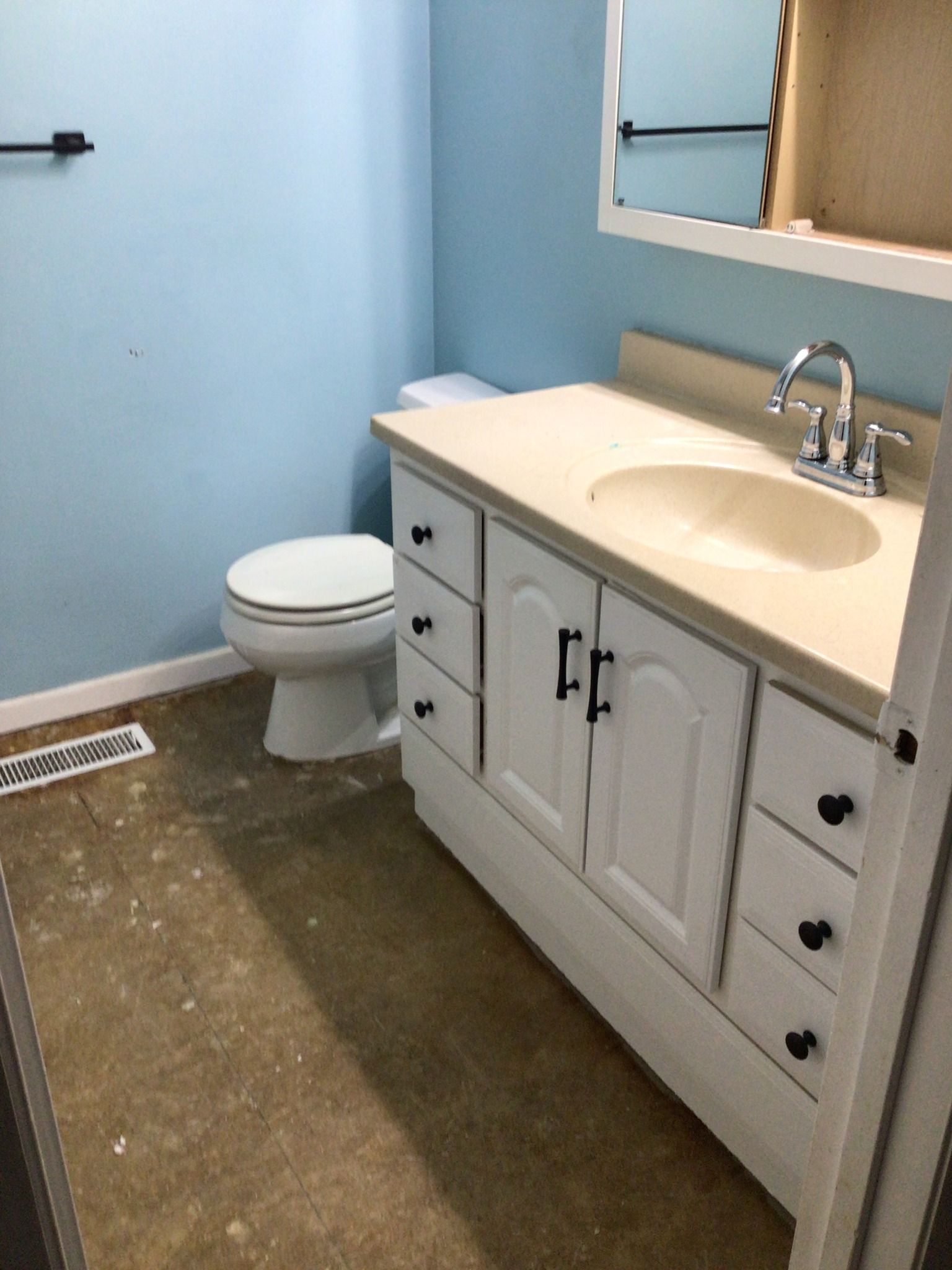 A bathroom with a toilet , sink and mirror.