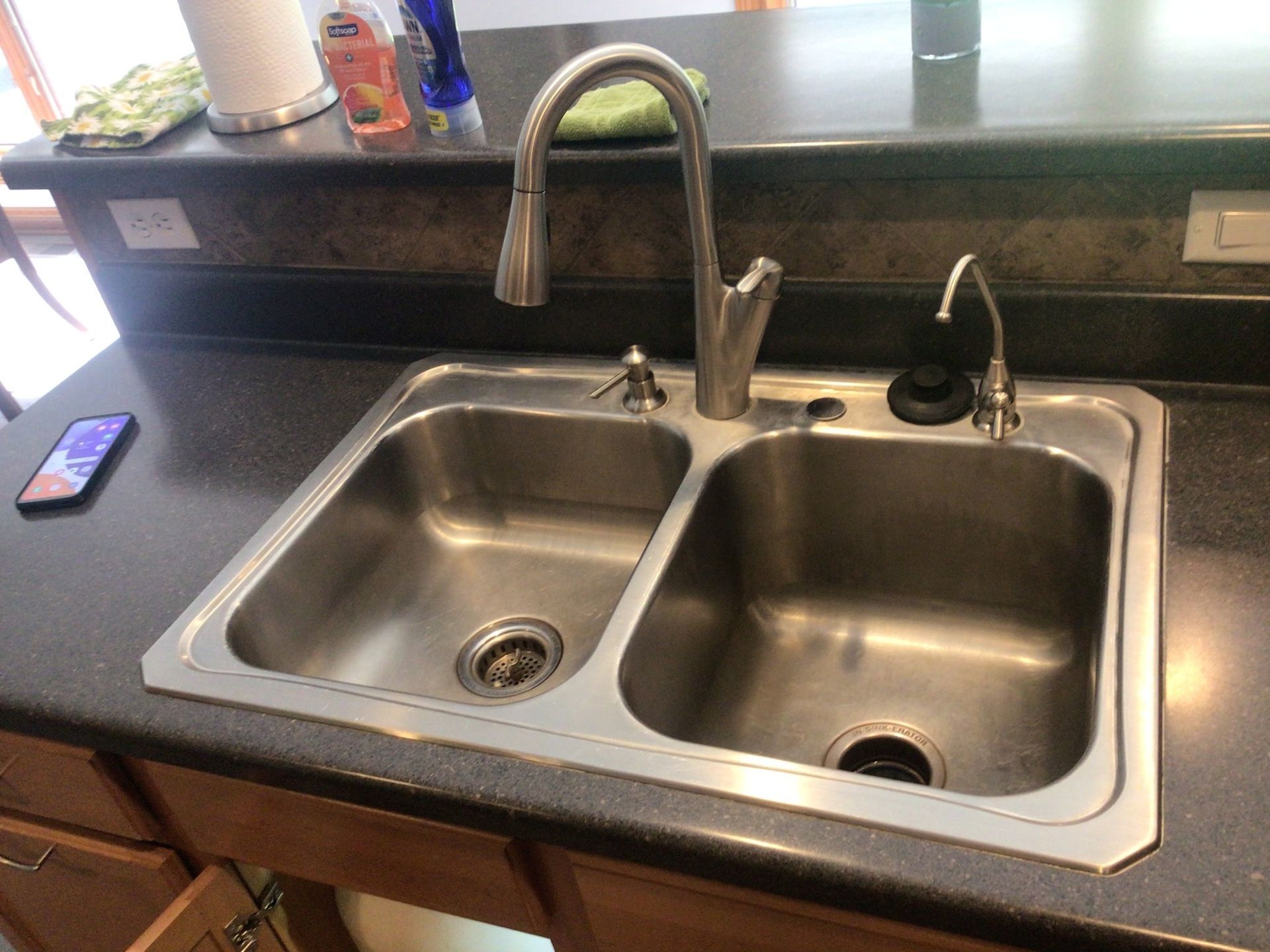 A kitchen sink with two sinks and a faucet on a counter.