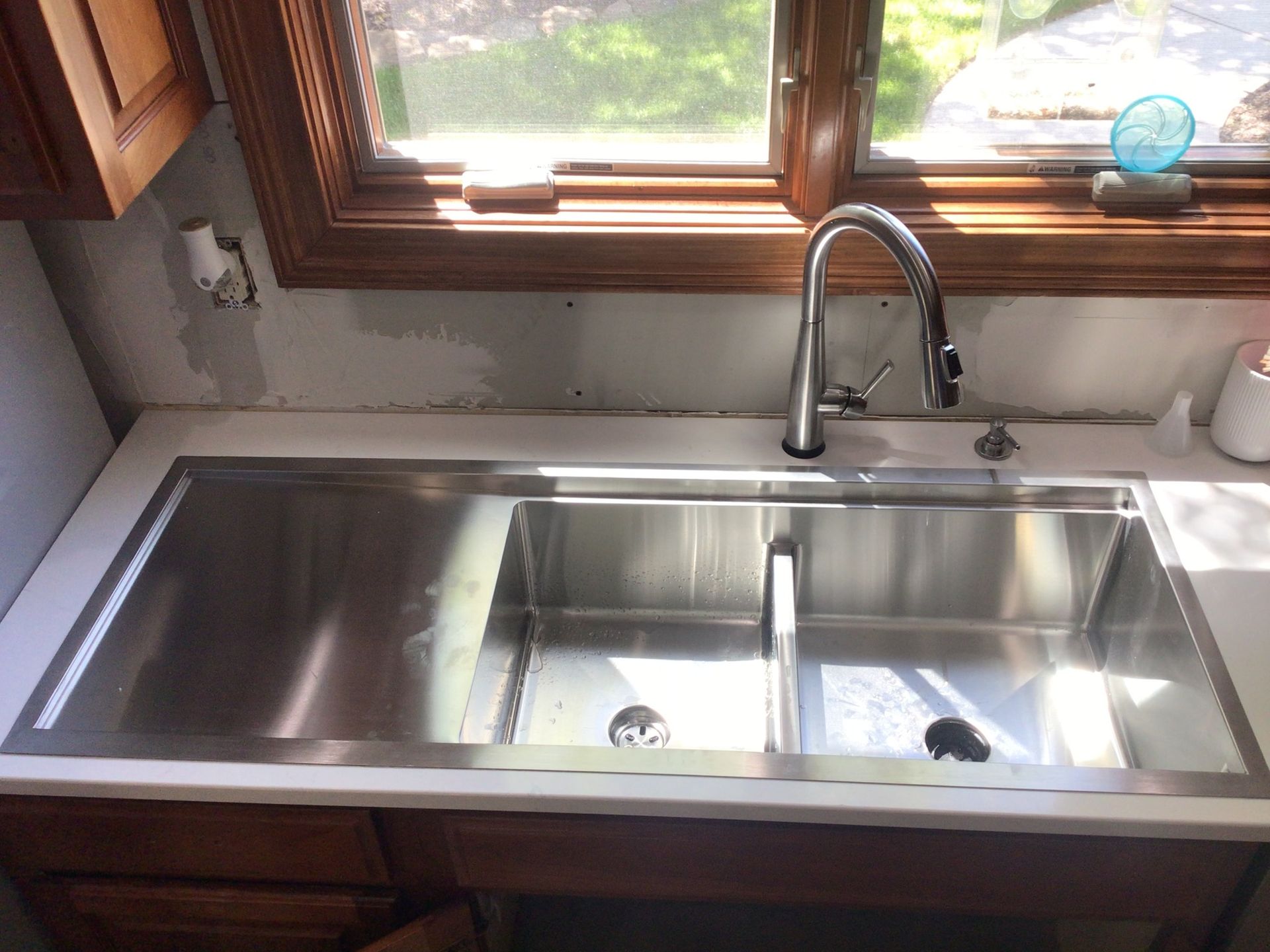 A stainless steel kitchen sink is sitting on a counter next to a window.