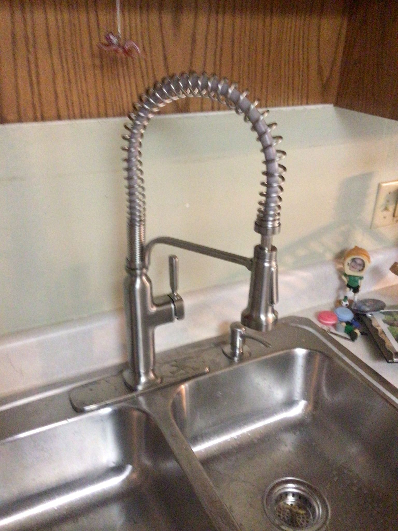A kitchen sink with a stainless steel faucet and soap dispenser.