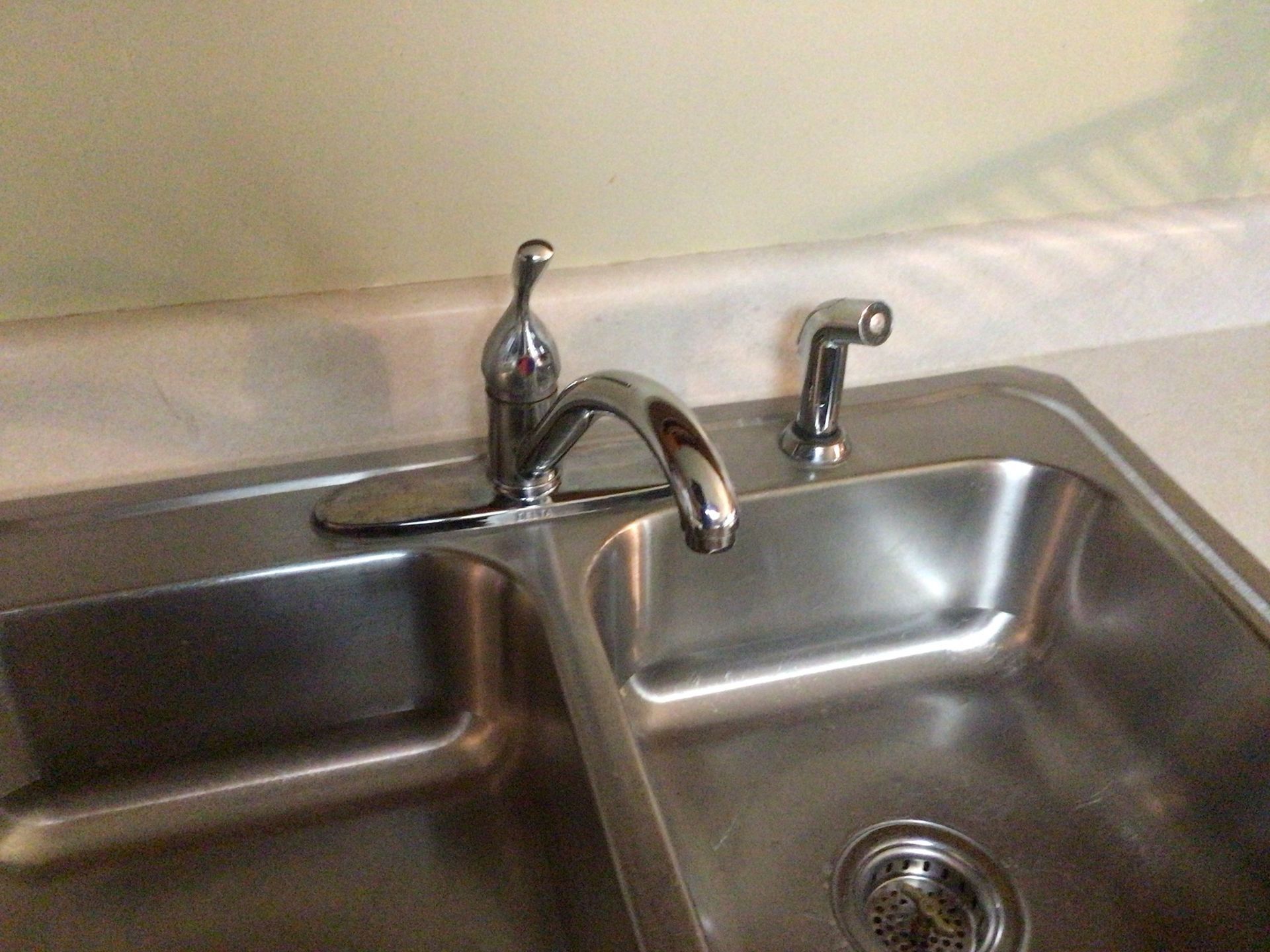 A close up of a stainless steel kitchen sink with a faucet