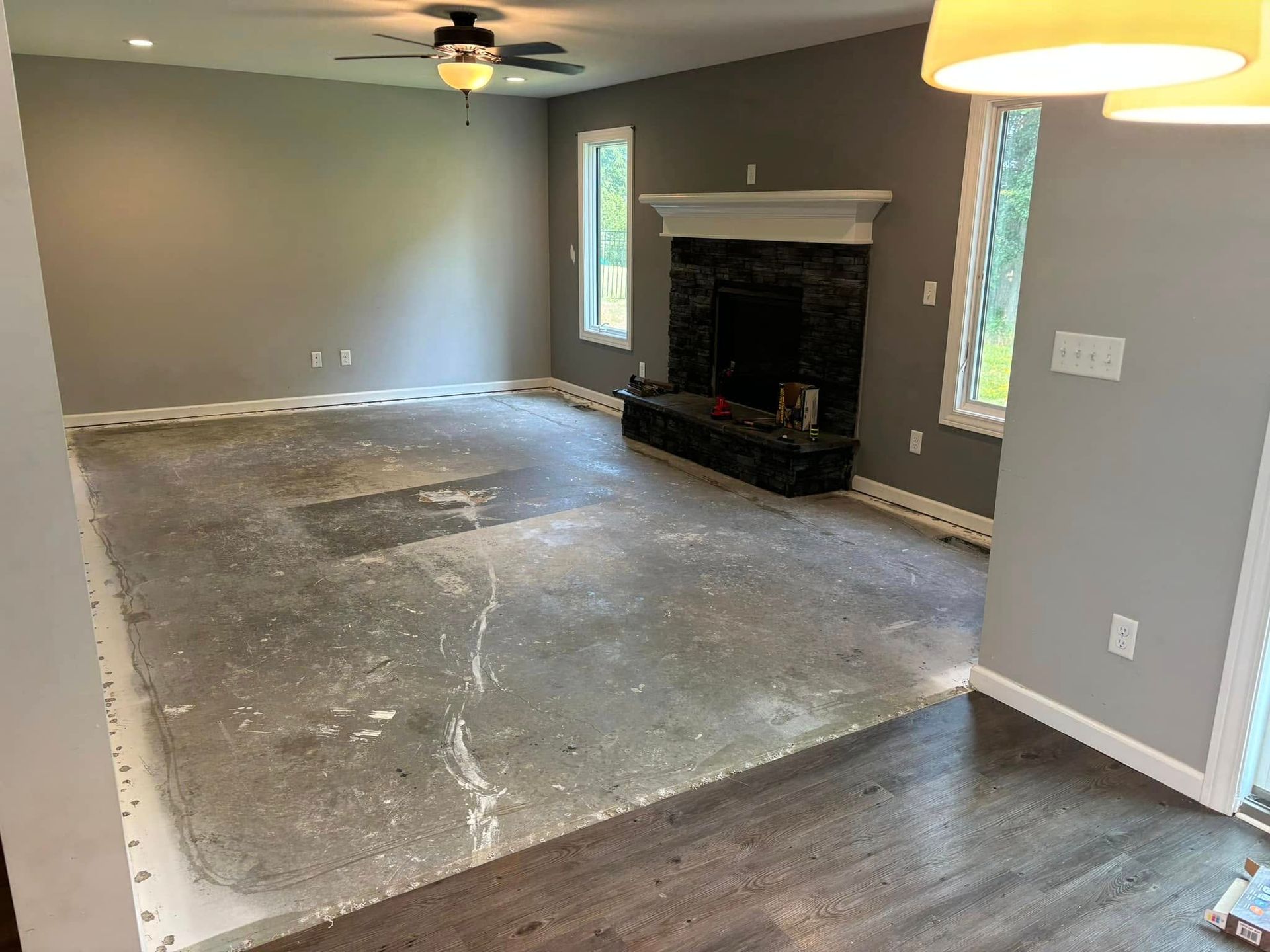 An empty living room with a fireplace and a ceiling fan.