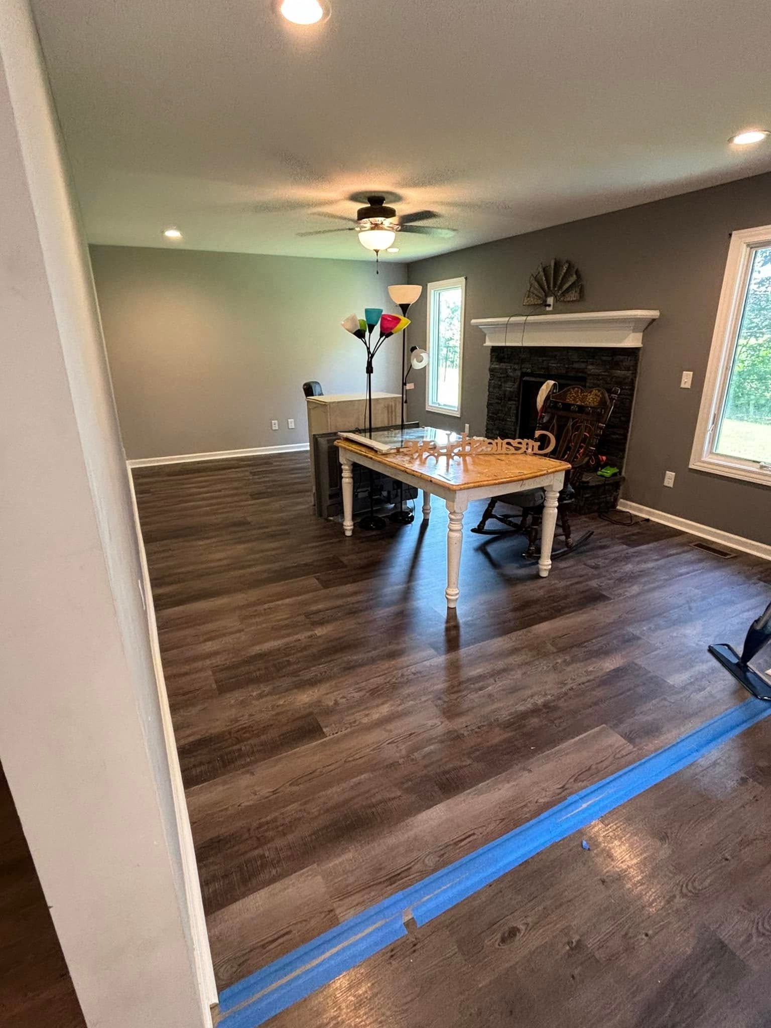A living room with hardwood floors , a table and a fireplace.