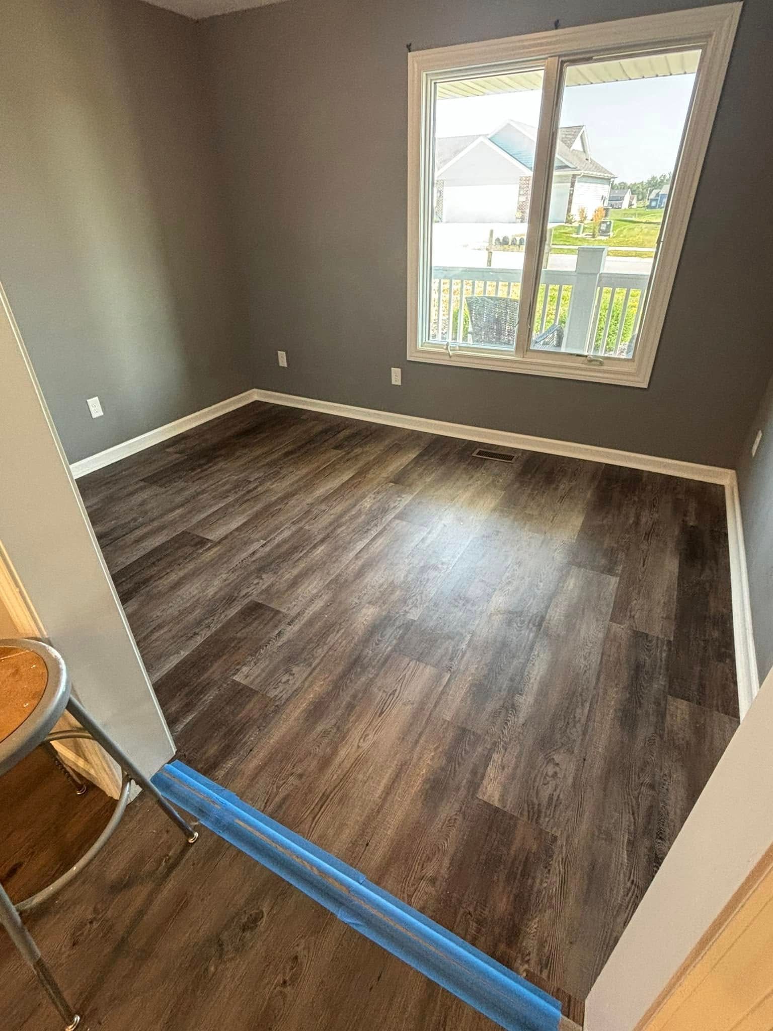 An empty room with hardwood floors and a window.