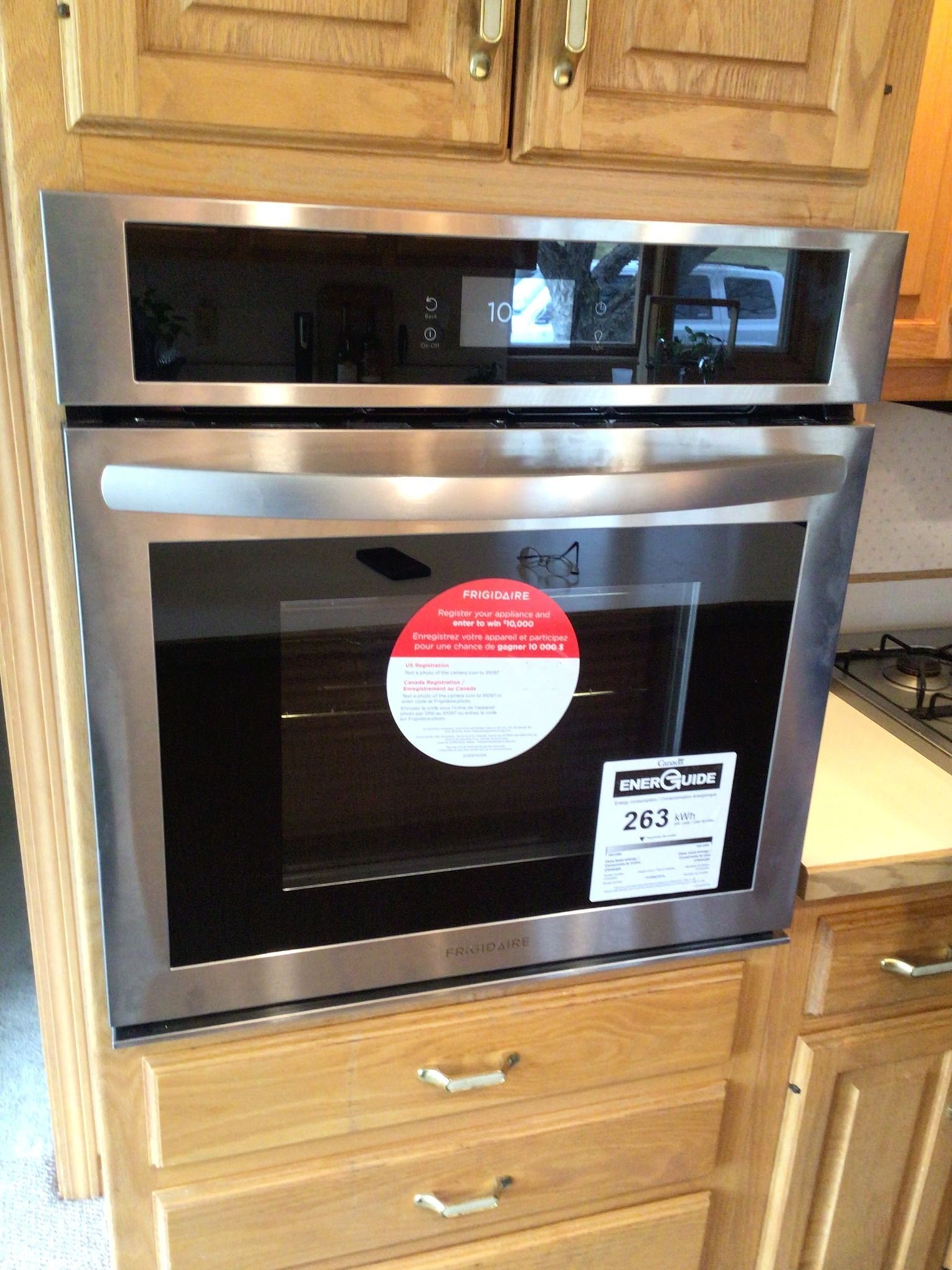 A stainless steel oven is sitting on top of a wooden cabinet.