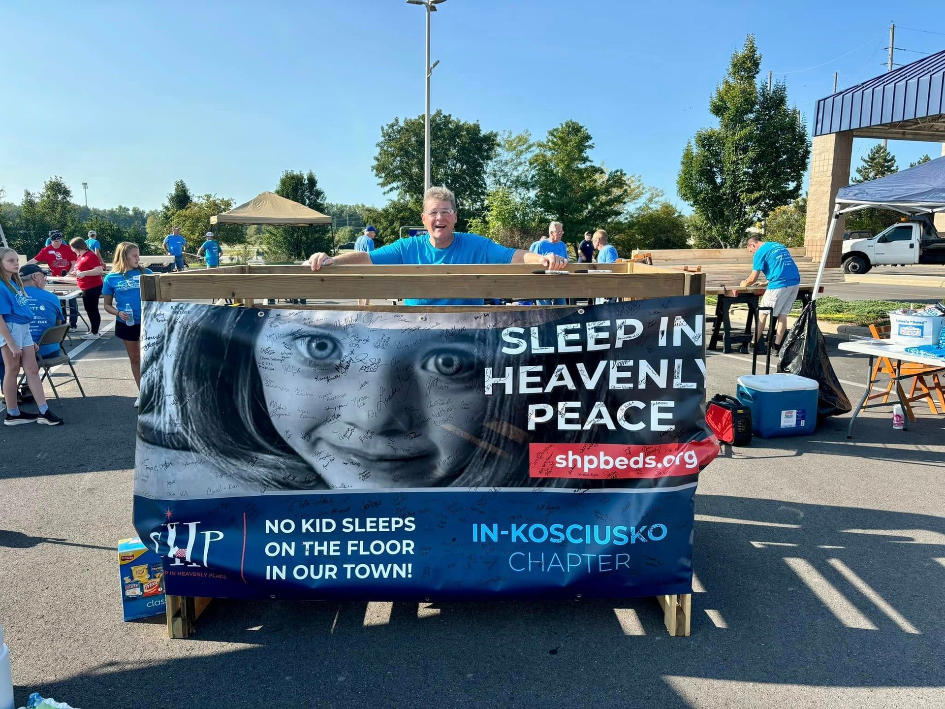 A man is standing behind a sign that says sleep in heavenly peace.