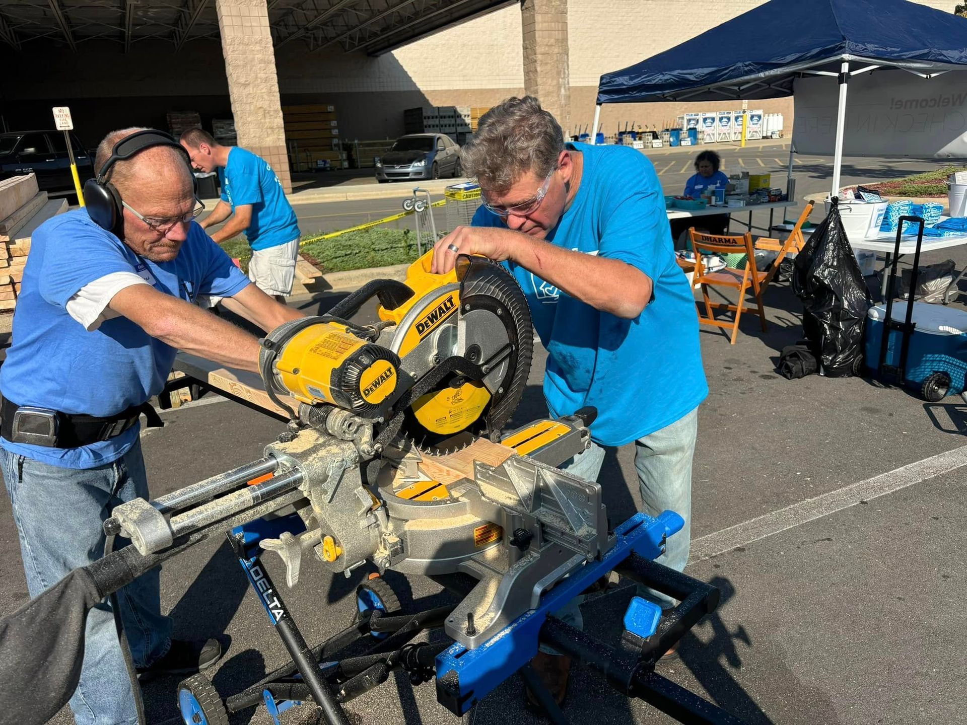Two men are working on a circular saw in a parking lot.