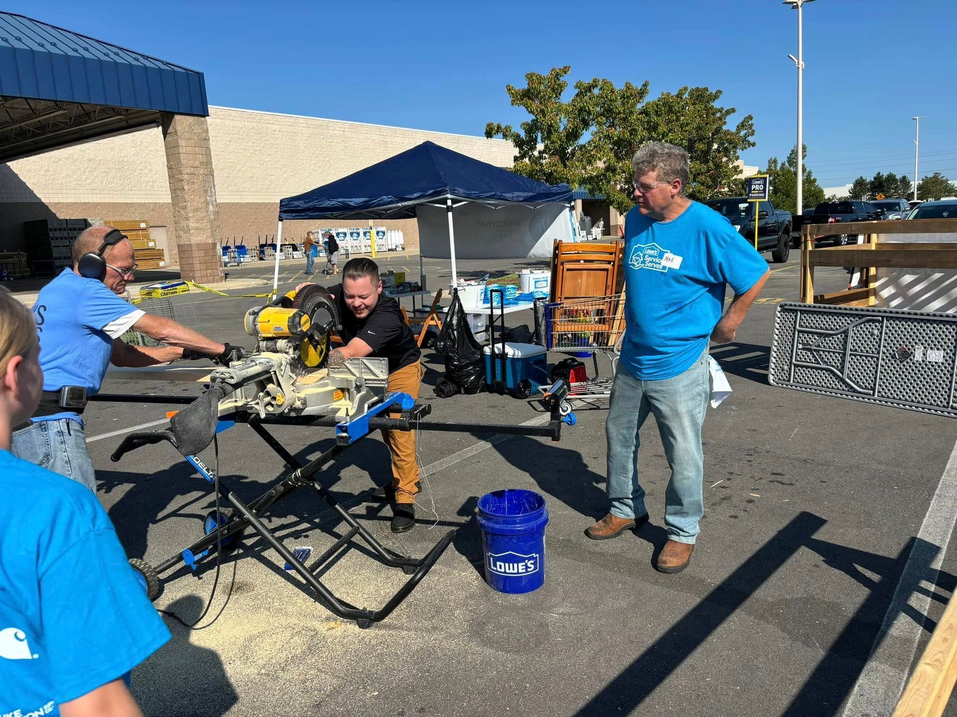 A group of men are working on a saw in a parking lot.