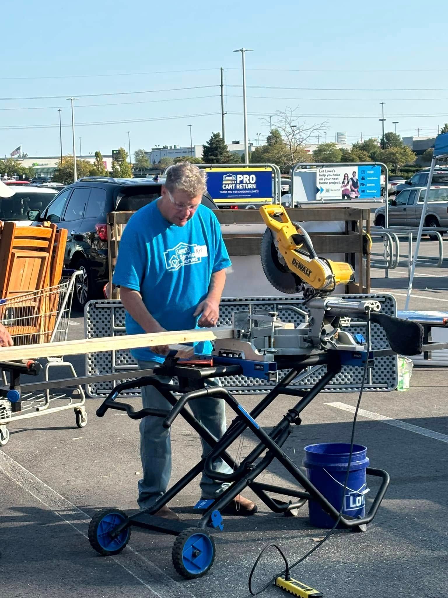 A man in a blue shirt is cutting a piece of wood