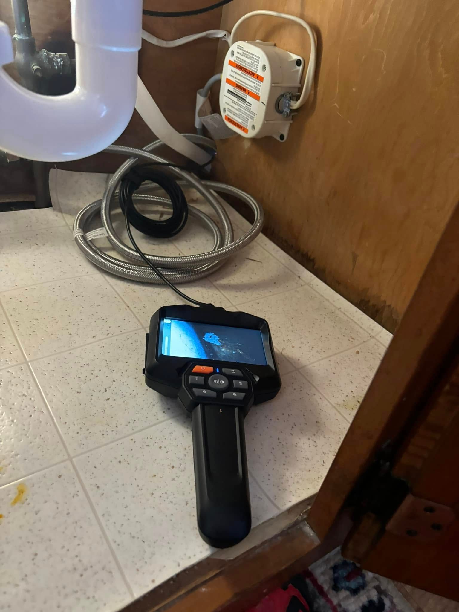 A camera is sitting on a counter next to a pipe.