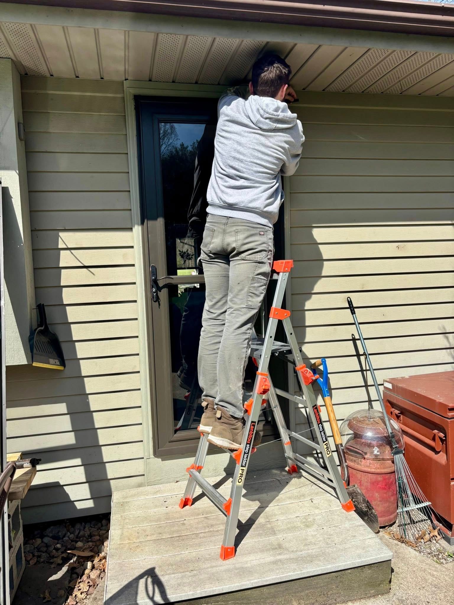 A man is standing on a ladder in front of a house.