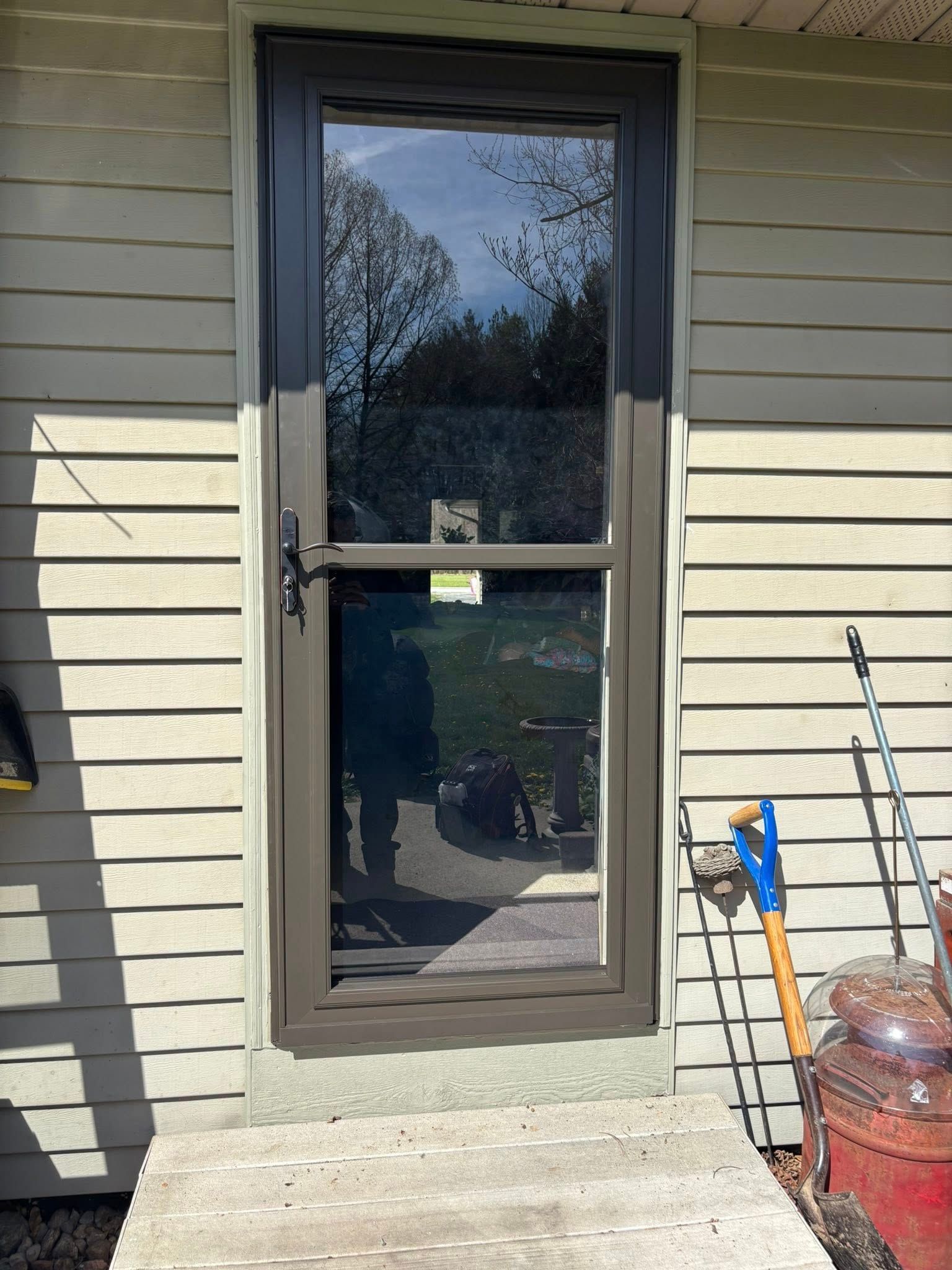 A door with a glass window is on the side of a house.