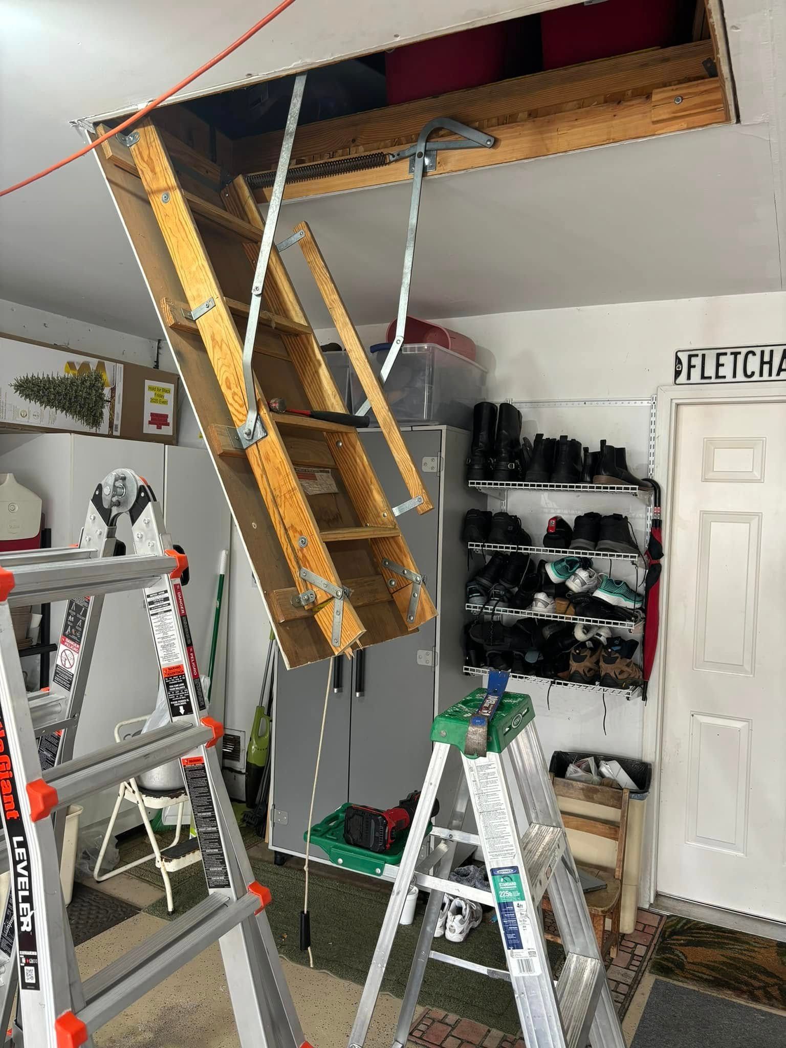 A wooden ladder is hanging from the ceiling of a garage.