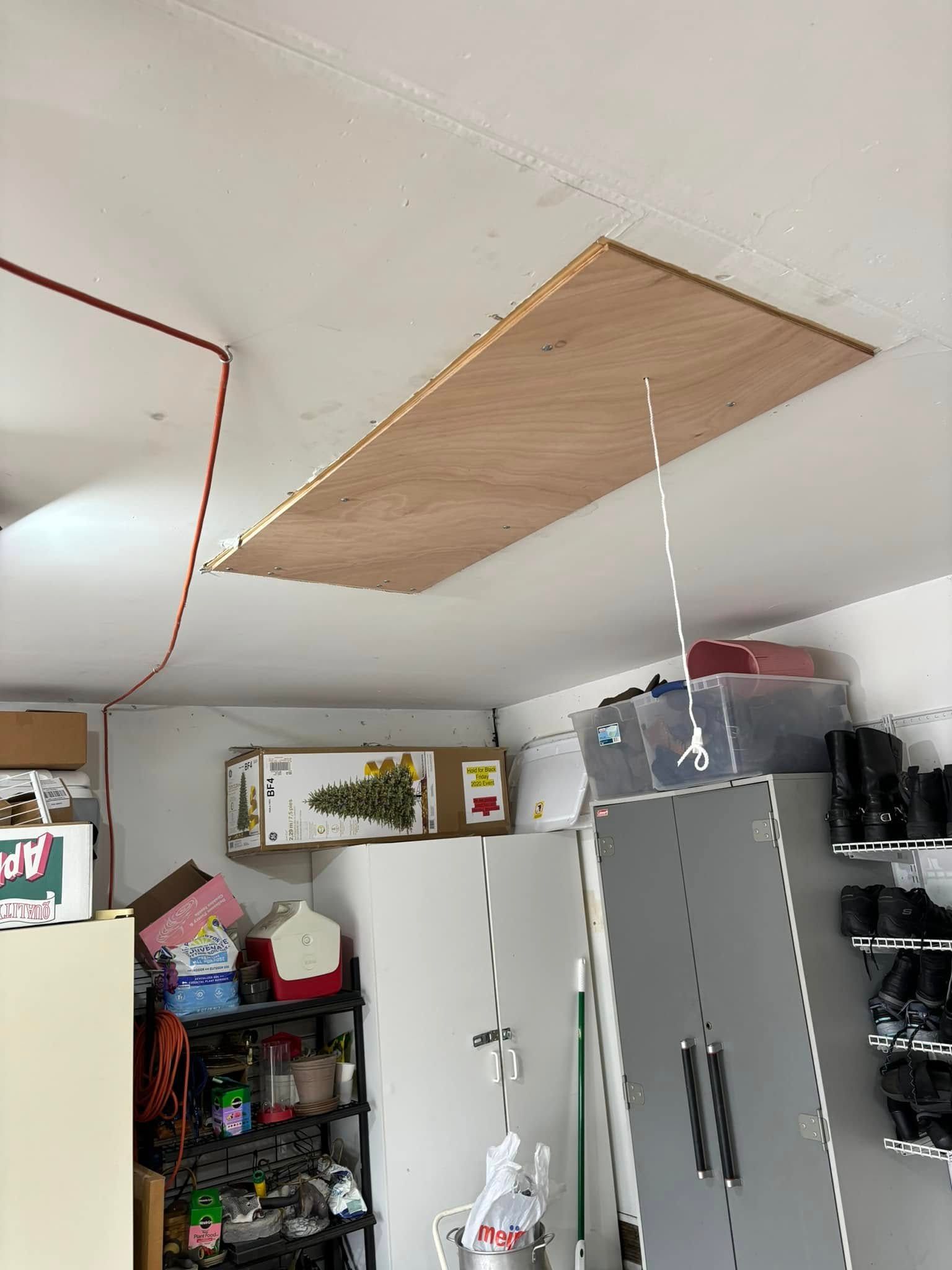 A wooden ladder is hanging from the ceiling of a garage.