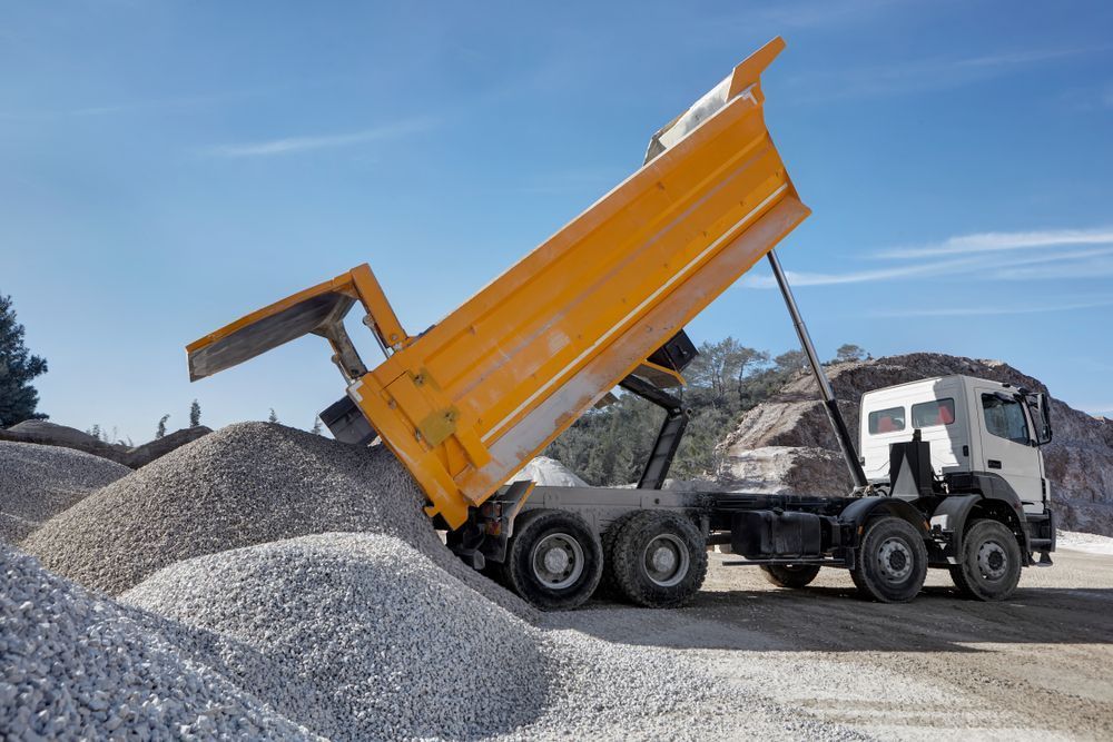A Dump Truck Is Dumping Gravel Into A Pile Of Gravel — Tuscany Concreting In Airlie Beach, QLD