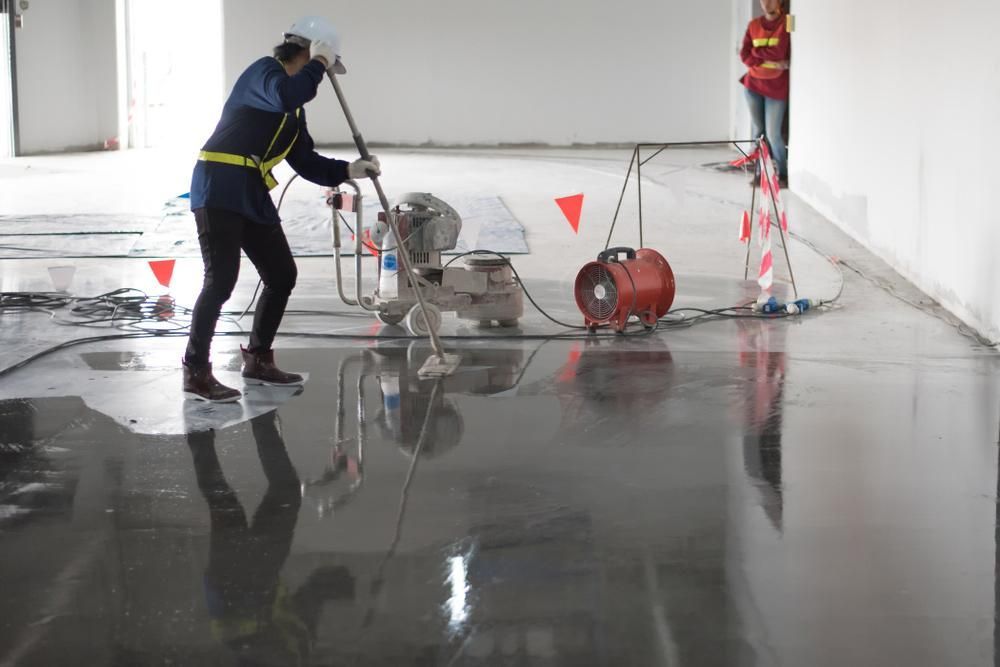 A Man Is Polishing A Concrete Floor With A Machine — Tuscany Concreting In Cannonvale, QLD
