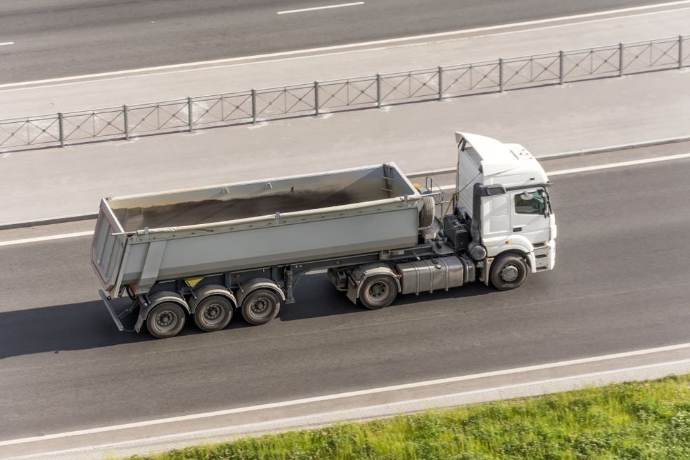 A Dump Truck Is Driving Down A Highway — Tuscany Concreting In Cannonvale, QLD
