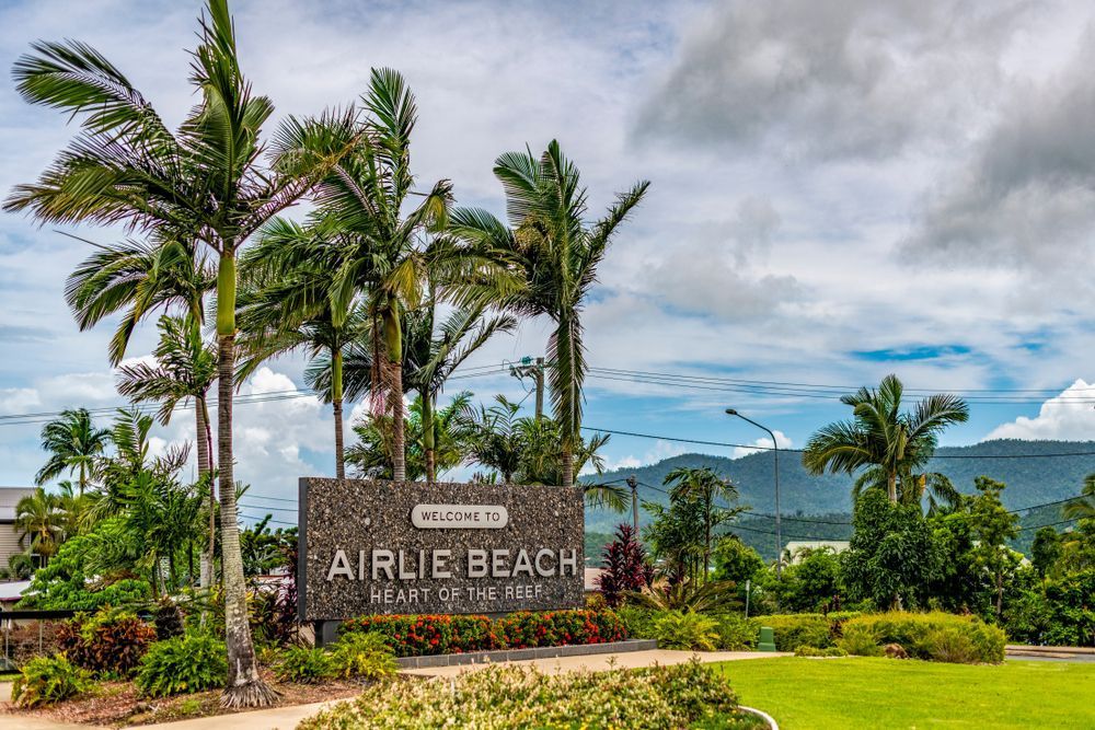 A Sign For Airlie Beach Is Surrounded By Palm Trees — Tuscany Concreting In Airlie Beach, QLD