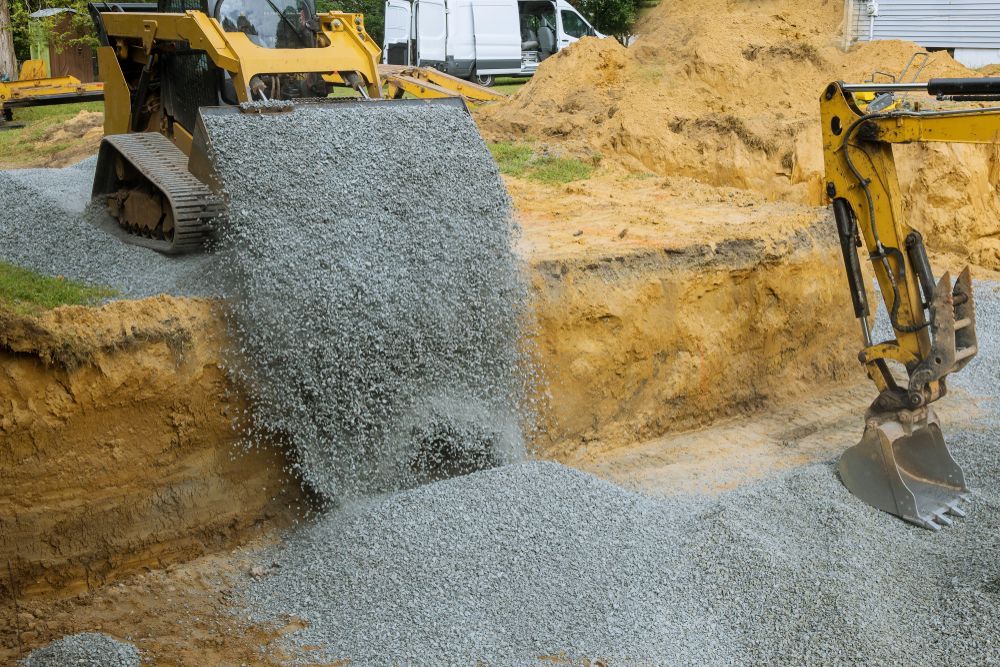 A Construction Worker Is Sitting On A Small Excavator At A Construction Site — Tuscany Concreting In Cannonvale, QLD