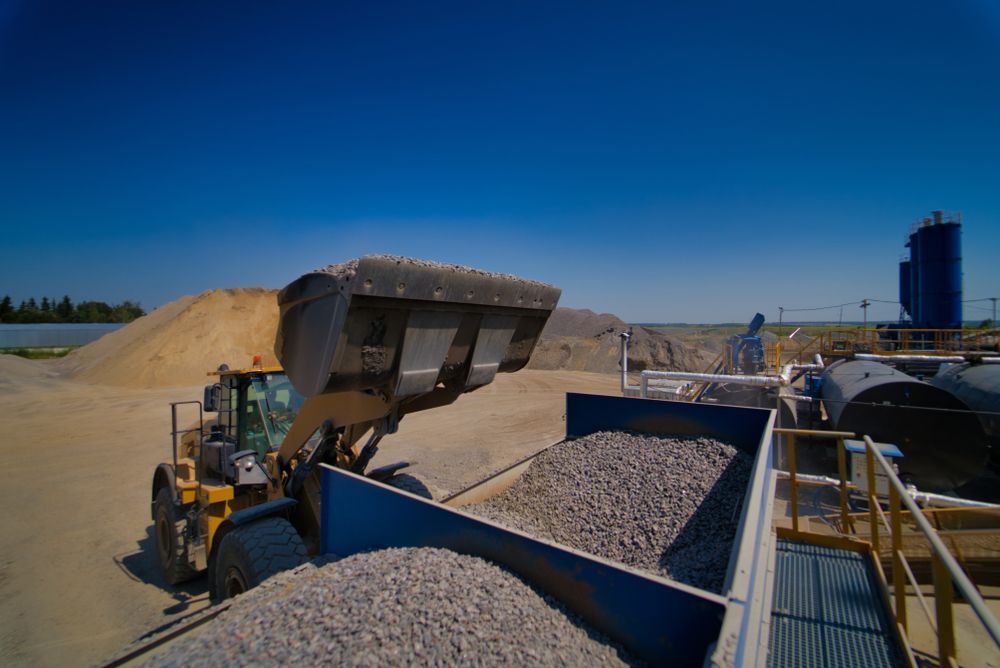 A Bulldozer Is Loading Gravel Into A Truck — Tuscany Concreting In Whitsundays, QLD