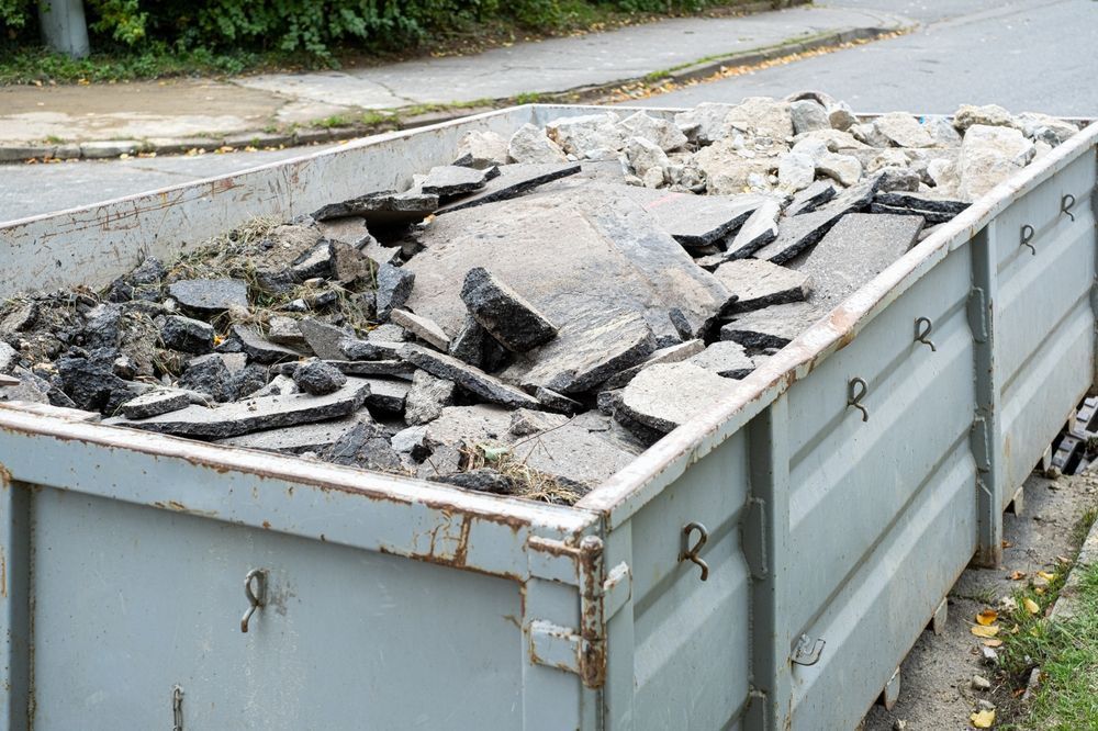 A Dumpster Filled With Rocks And Dirt Is Sitting On The Side Of The Road — Tuscany Concreting In Cannonvale, QLD