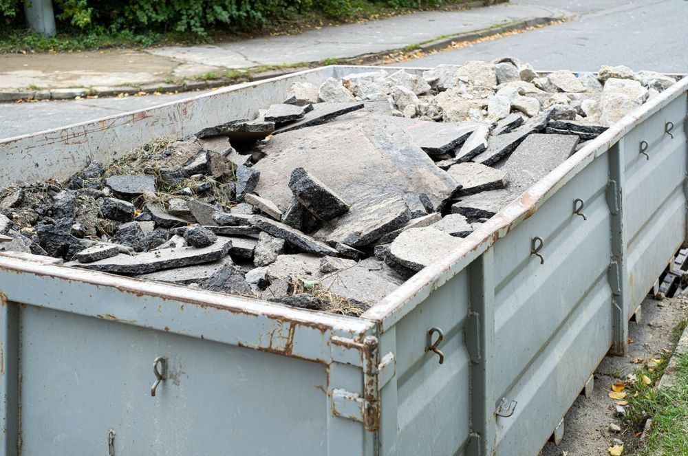 A Dumpster Filled With Rocks And Dirt Is Sitting On The Side Of The Road — Tuscany Concreting In Bowen, QLD