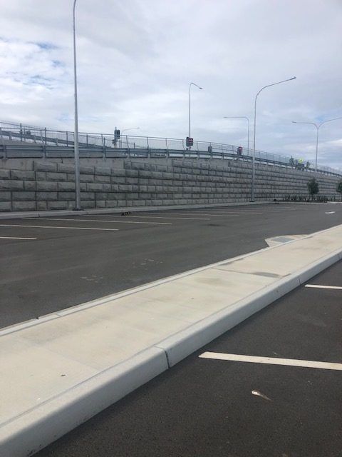 An Empty Parking Lot With A Brick Wall In The Background — Tuscany Concreting In Cannonvale, QLD