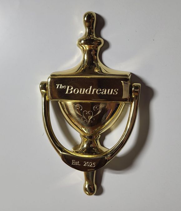 Hands holding a small gift box wrapped in brown paper with a gold ribbon.