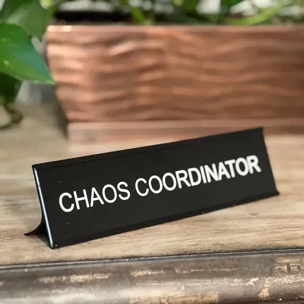 A black desk sign with white text that reads 