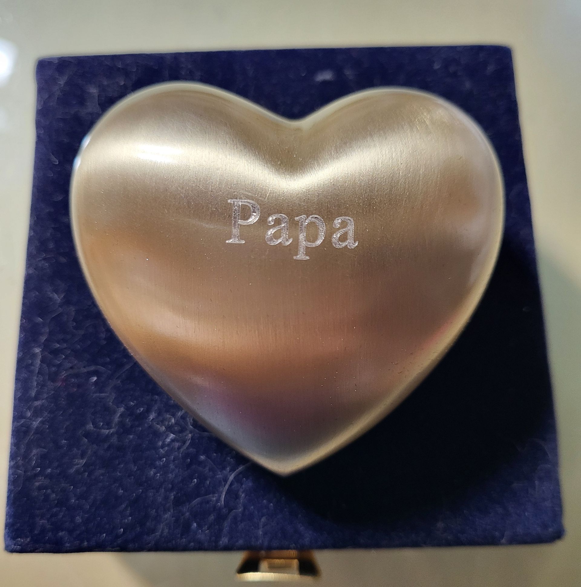 A heart-shaped gold-colored keepsake urn engraved with 