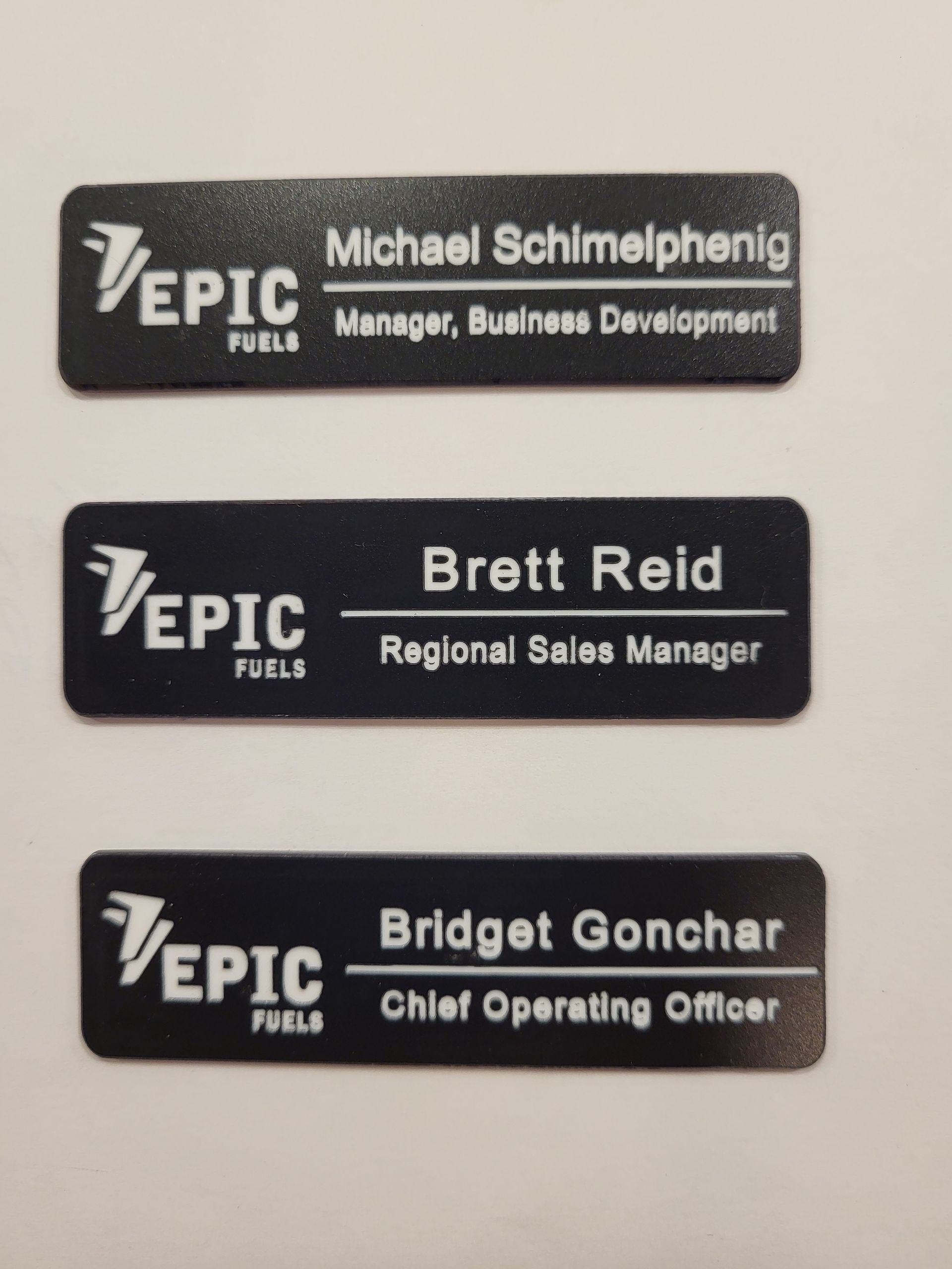 Three black rectangular name tags with the Epic Fuels logo, displaying names and titles for Michael, Brett, and Bridget.