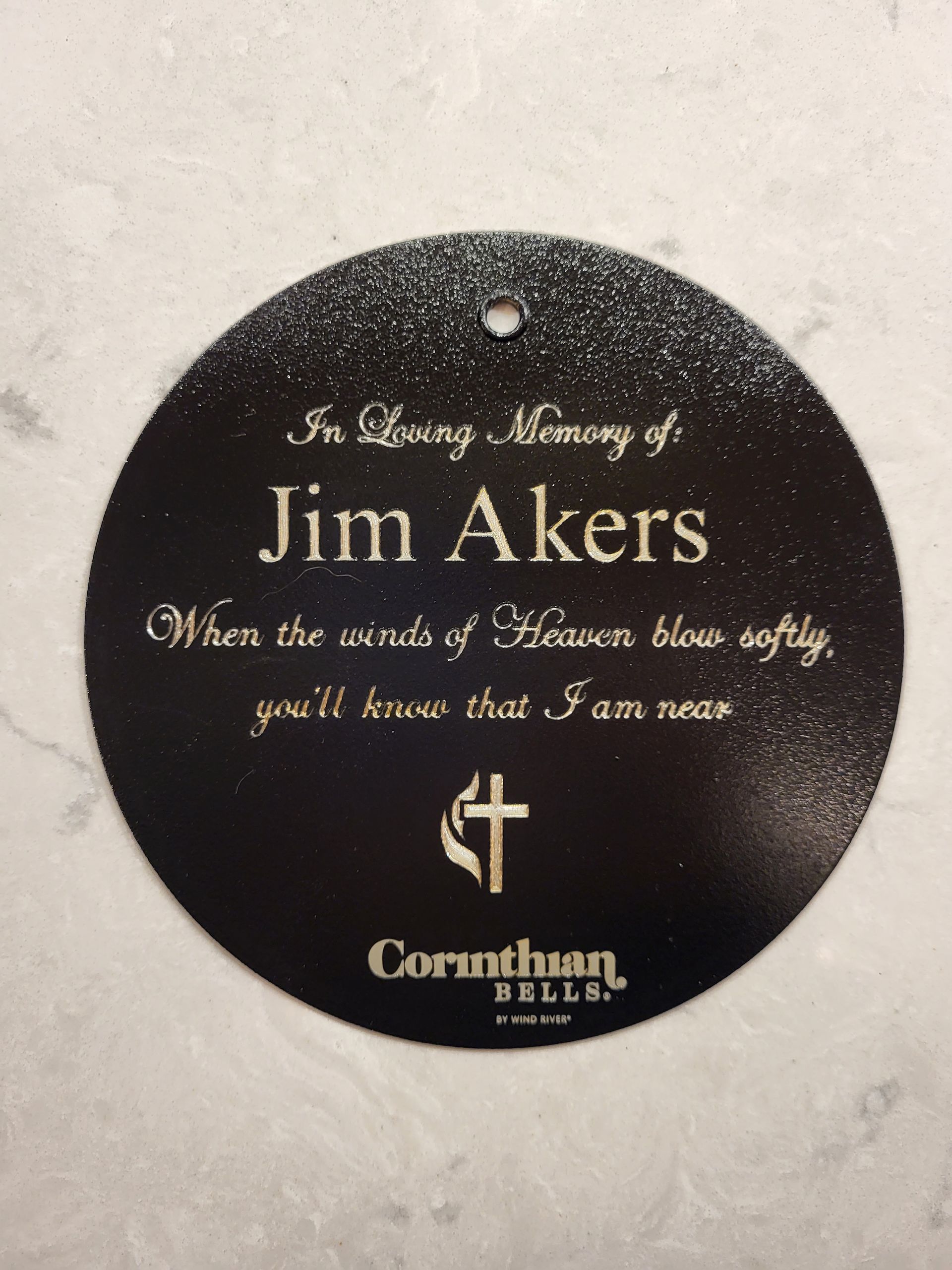 A black, circular memorial ornament engraved with the name 