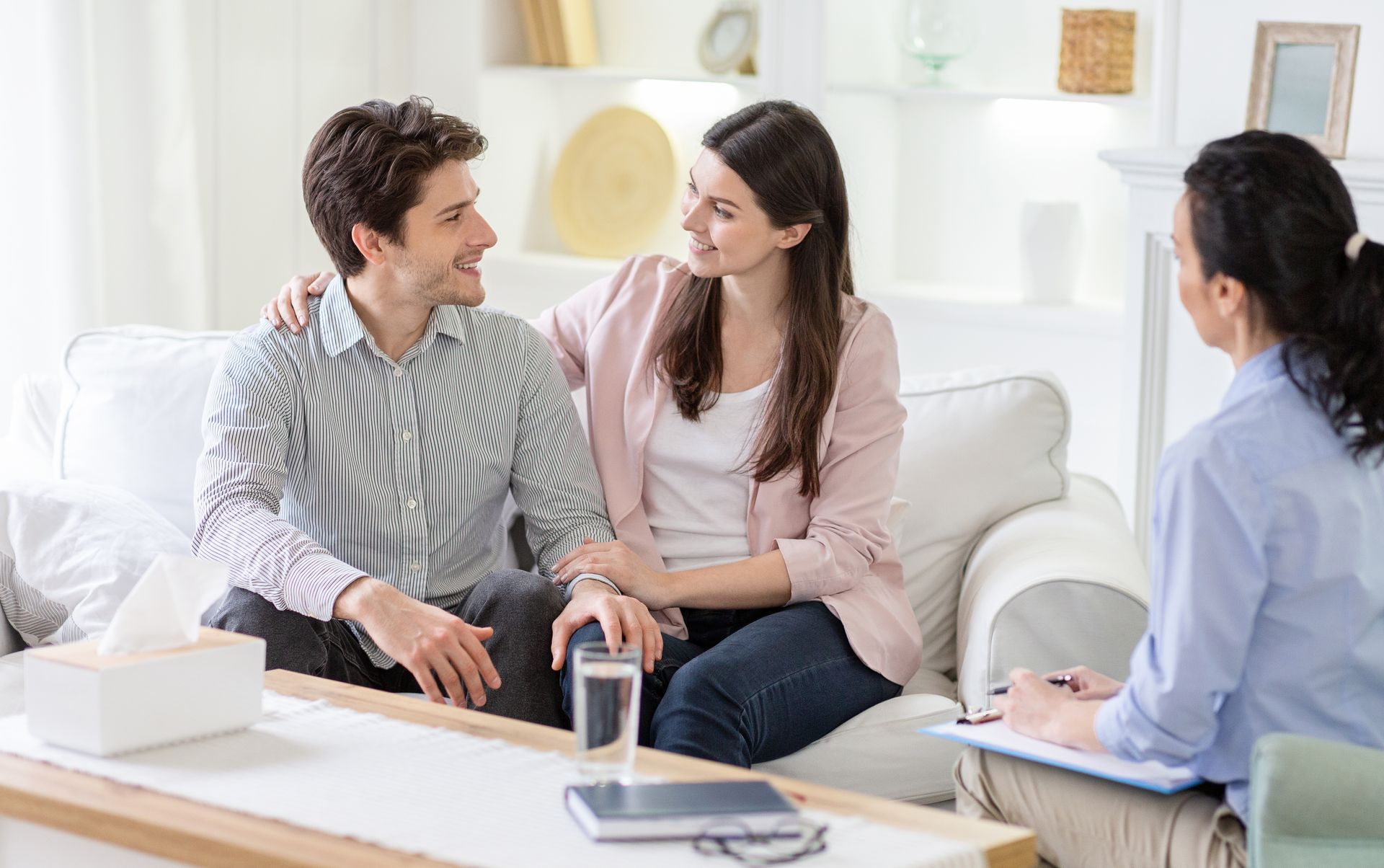 A man and a woman are sitting on a couch talking to a woman.