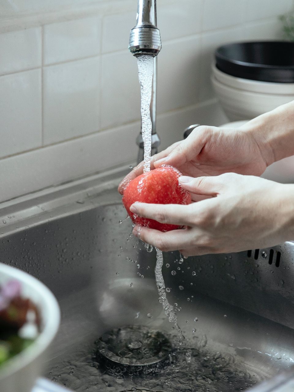 a person is washing an apple in a kitchen sink