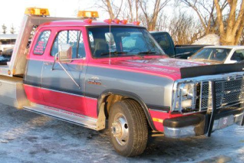 A red and gray tow truck is parked in the snow.