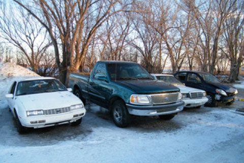 A group of cars are parked in a snowy parking lot.