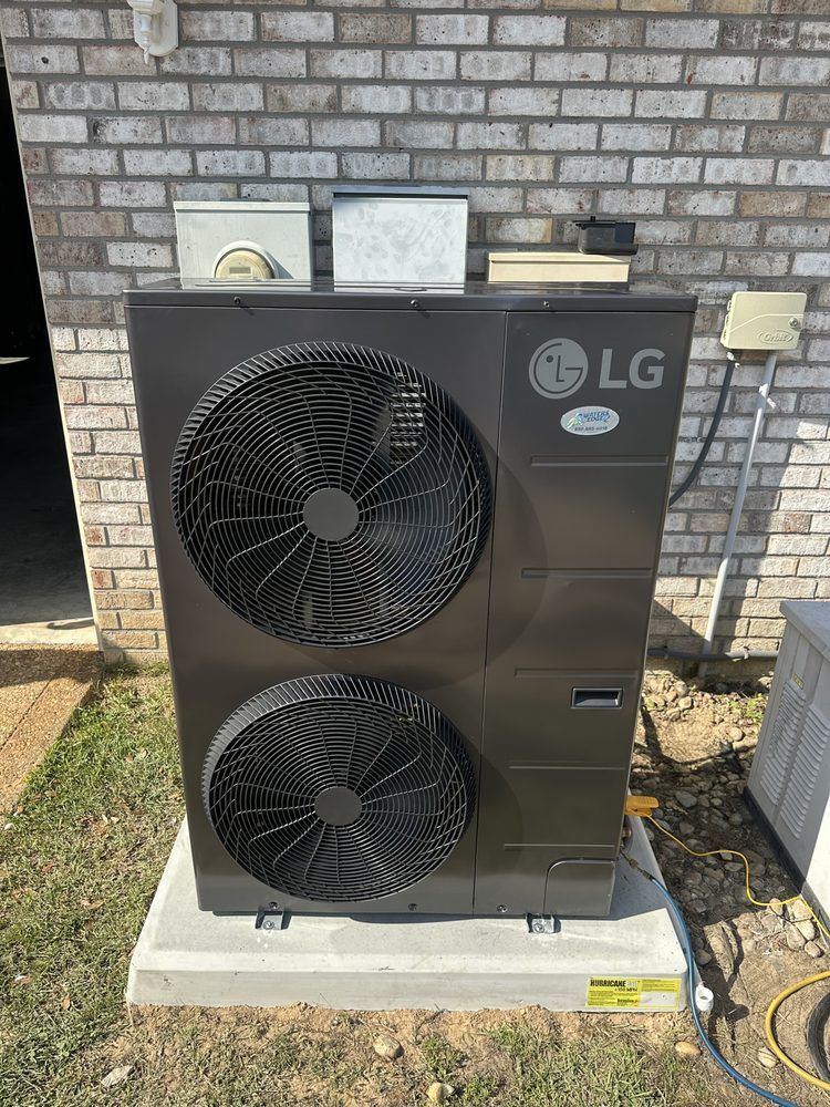 LG air source heat pump on a concrete pad near a brick wall.