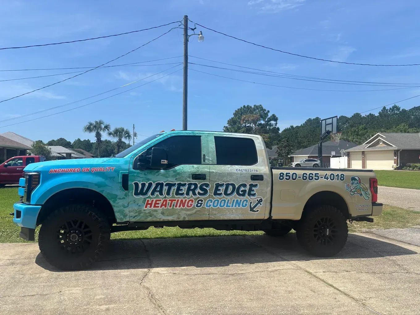 Waters Edge Heating & Cooling truck with blue and tan graphics parked on a street.