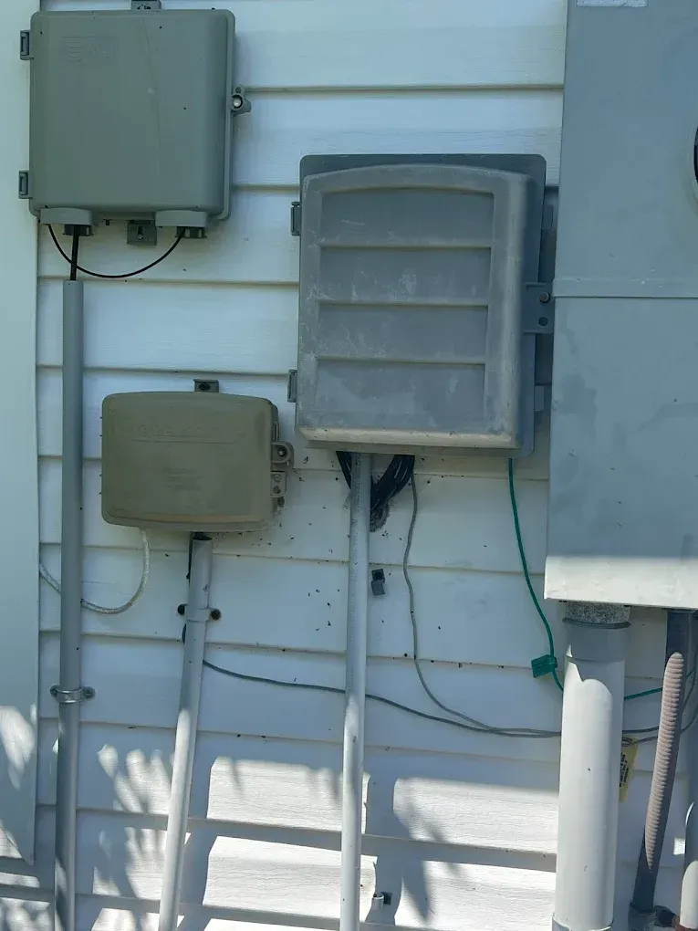 Various utility boxes mounted on a white house exterior.