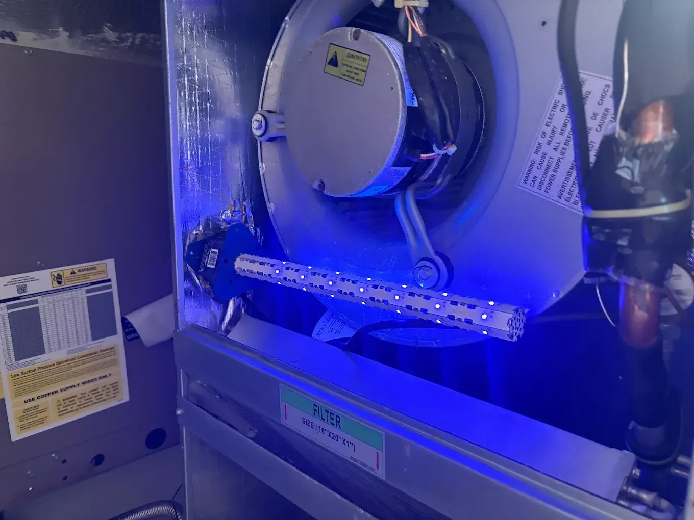 Interior view of an HVAC system, a blue UV light is illuminated inside the air handler.