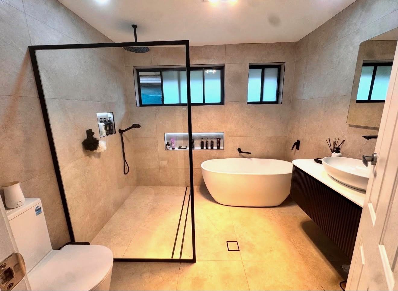 Modern bathroom with freestanding tub, glass shower, double sinks, and beige tile walls. — Start 2 Finish Plumbing in Yagoona, NSW