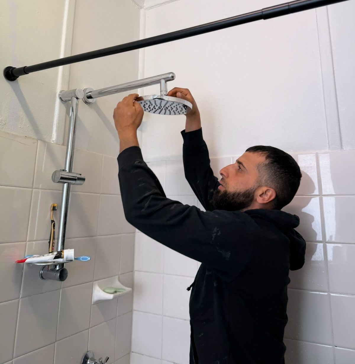 Man installing a showerhead on a tiled shower wall with a wrench — Start 2 Finish Plumbing in Yagoona, NSW