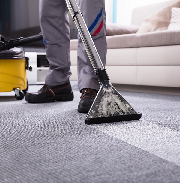 A person is using a vacuum cleaner to clean a carpet in a living room.