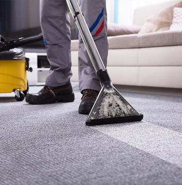 A person is using a vacuum cleaner to clean a carpet in a living room.